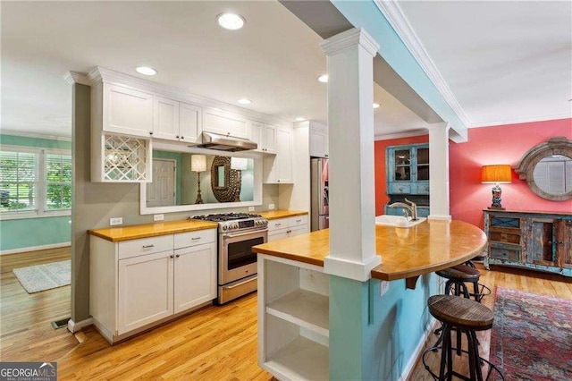 kitchen featuring appliances with stainless steel finishes, white cabinetry, butcher block counters, and ornate columns