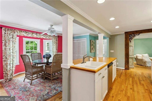 kitchen with decorative columns, stainless steel dishwasher, ceiling fan, sink, and white cabinets