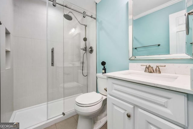 bathroom featuring vanity, a shower with door, tile patterned flooring, toilet, and ornamental molding