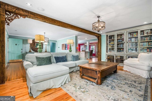 living room with hardwood / wood-style floors, a notable chandelier, crown molding, and beamed ceiling