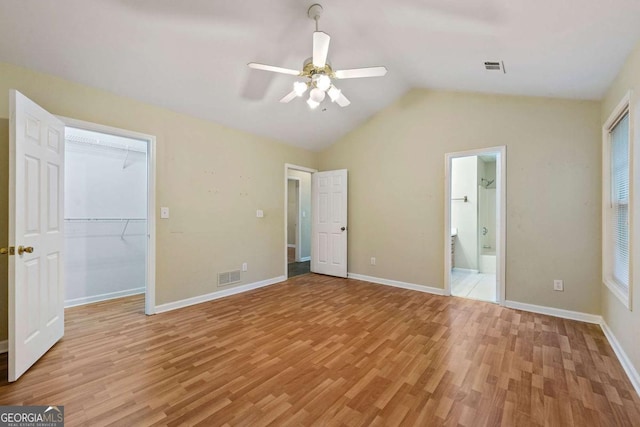 unfurnished bedroom featuring ceiling fan, ensuite bath, lofted ceiling, and light hardwood / wood-style flooring