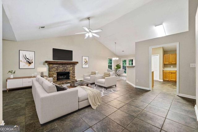 living room featuring a stone fireplace, dark tile patterned floors, high vaulted ceiling, and ceiling fan with notable chandelier