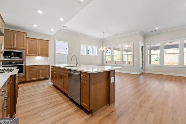 kitchen featuring a wealth of natural light, appliances with stainless steel finishes, brown cabinetry, and a sink