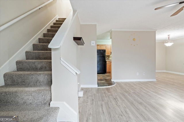 staircase with crown molding, ceiling fan, and hardwood / wood-style flooring