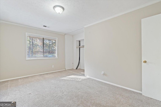 carpeted empty room featuring crown molding and a textured ceiling