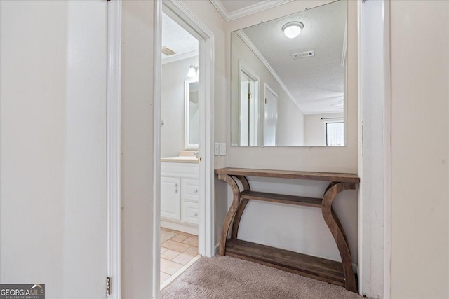 hallway with light colored carpet, ornamental molding, and a textured ceiling