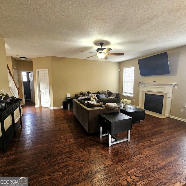 living room featuring ceiling fan, dark hardwood / wood-style floors, and a textured ceiling