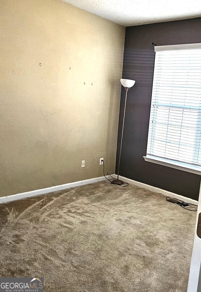 carpeted empty room featuring a textured ceiling