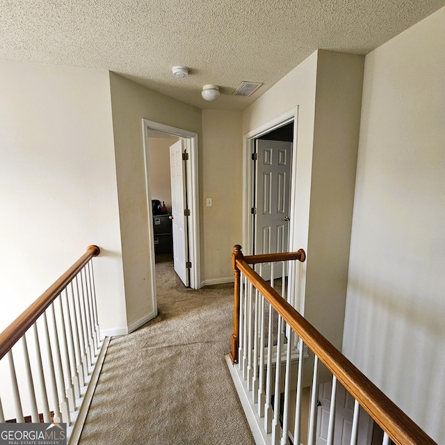 hall with light carpet and a textured ceiling