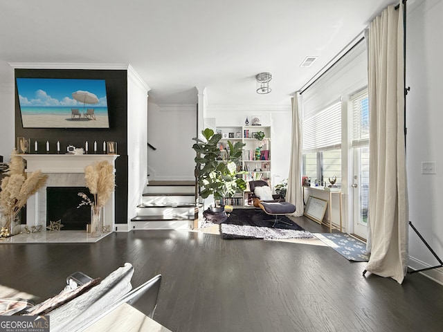 interior space featuring a fireplace, ornamental molding, and hardwood / wood-style flooring