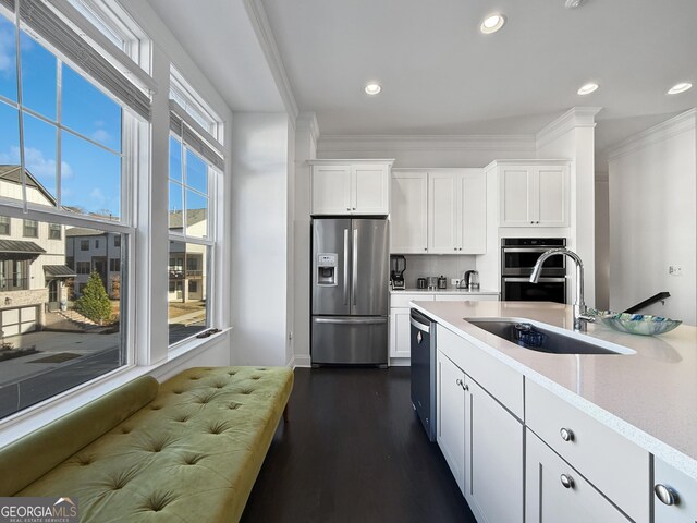 kitchen with dark wood-type flooring, white cabinets, ornamental molding, and appliances with stainless steel finishes