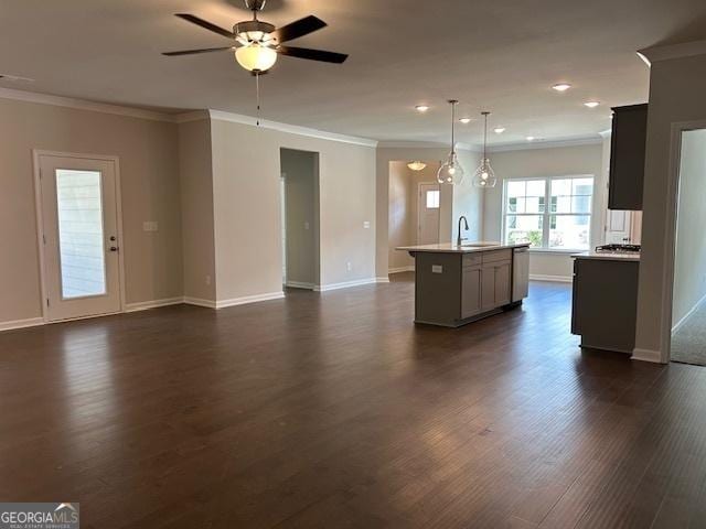 kitchen featuring dark hardwood / wood-style flooring, a kitchen island with sink, crown molding, sink, and hanging light fixtures