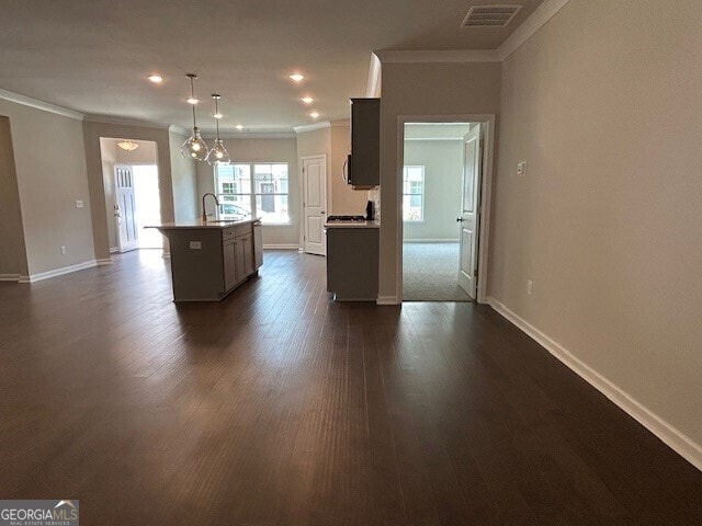 kitchen with crown molding, an island with sink, pendant lighting, and dark hardwood / wood-style floors