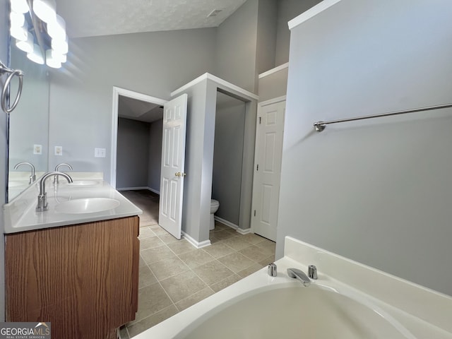 bathroom featuring vanity, a textured ceiling, vaulted ceiling, tile patterned flooring, and a tub