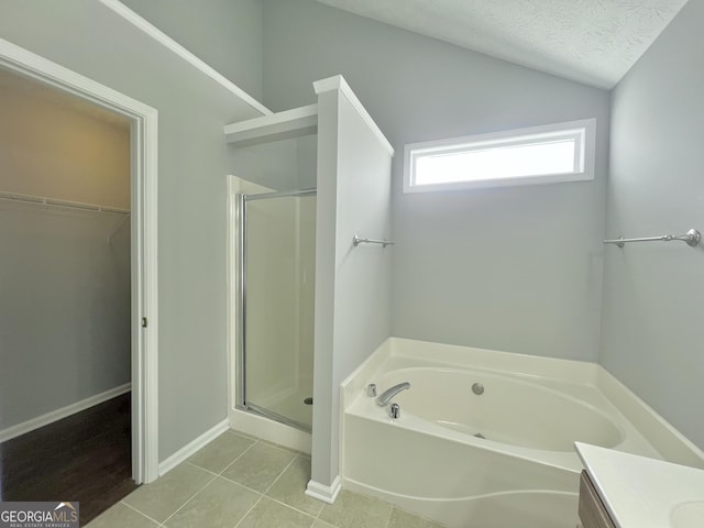 bathroom with tile patterned floors, shower with separate bathtub, lofted ceiling, and a textured ceiling