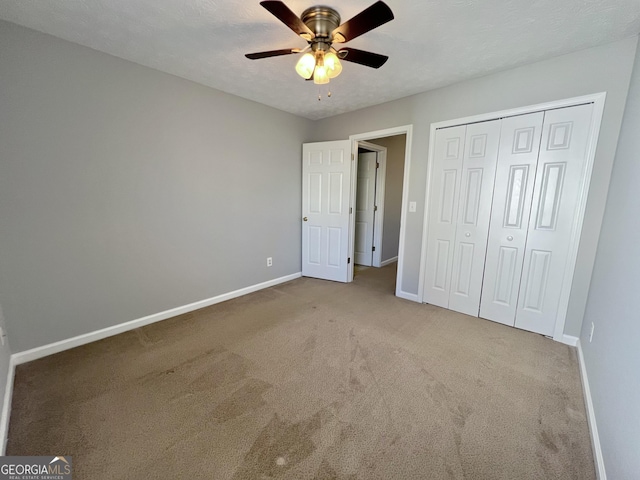 unfurnished bedroom featuring ceiling fan, a closet, carpet, and a textured ceiling