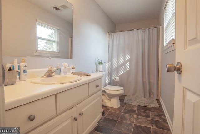 bathroom with walk in shower, vanity, and toilet