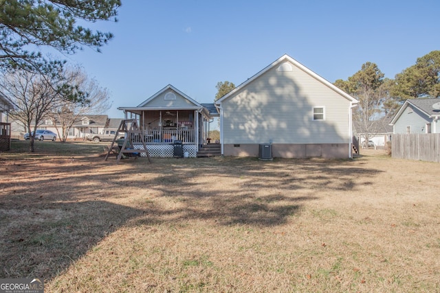 back of property with covered porch, a yard, and central air condition unit