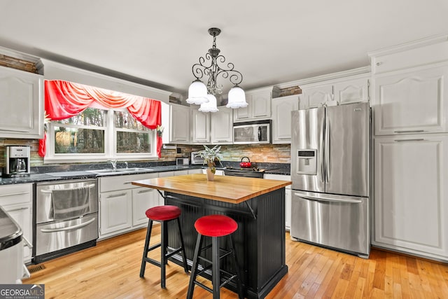 kitchen with stainless steel appliances, sink, butcher block counters, a kitchen island, and a breakfast bar area