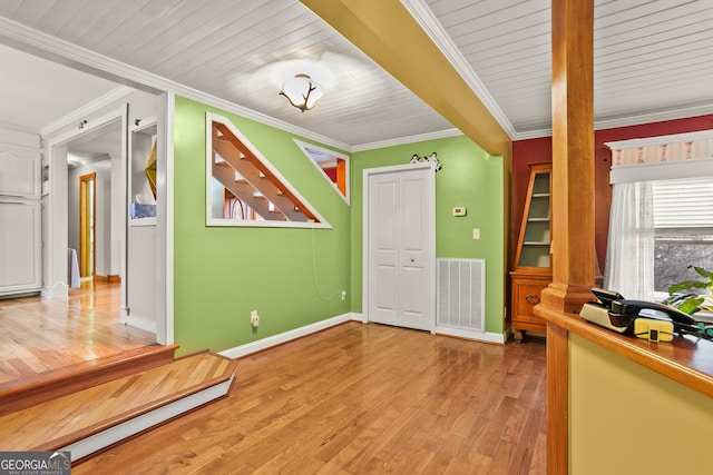 interior space with light hardwood / wood-style floors, ornamental molding, and wood ceiling