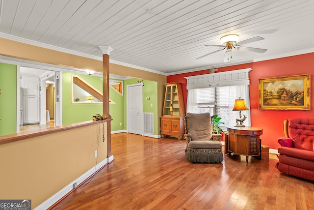 sitting room with wood-type flooring, wooden ceiling, ceiling fan, and crown molding