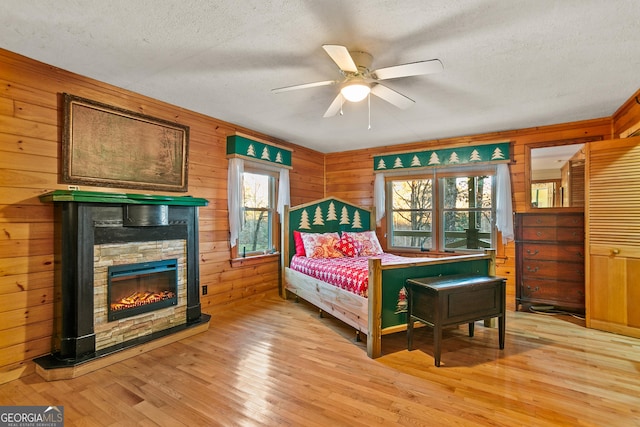 bedroom featuring light hardwood / wood-style floors, wooden walls, and multiple windows