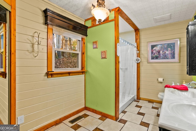 bathroom featuring a textured ceiling, toilet, walk in shower, and wooden walls