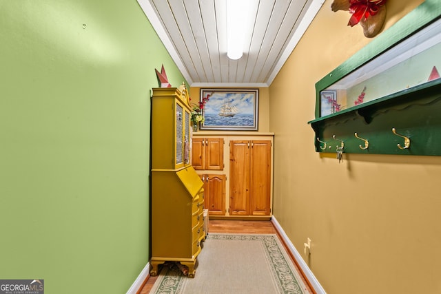 corridor featuring light hardwood / wood-style floors, wood ceiling, and ornamental molding