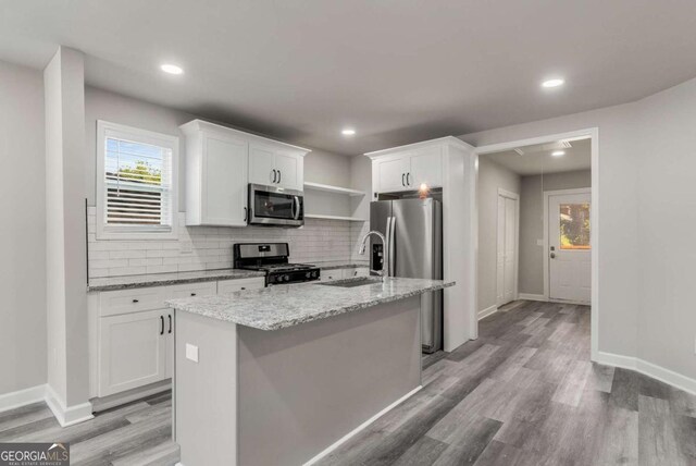 kitchen featuring a center island with sink, white cabinets, light hardwood / wood-style floors, and appliances with stainless steel finishes