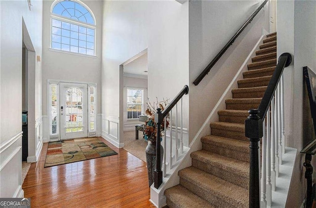 entryway with light hardwood / wood-style floors, a towering ceiling, and ornamental molding