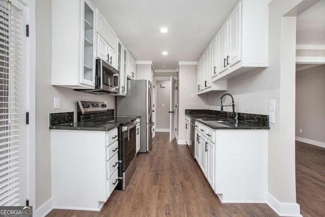 kitchen with dark wood-type flooring, white cabinets, sink, dark stone countertops, and appliances with stainless steel finishes