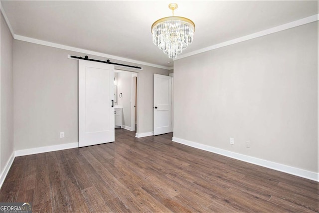 unfurnished bedroom with a barn door, dark hardwood / wood-style floors, an inviting chandelier, and crown molding