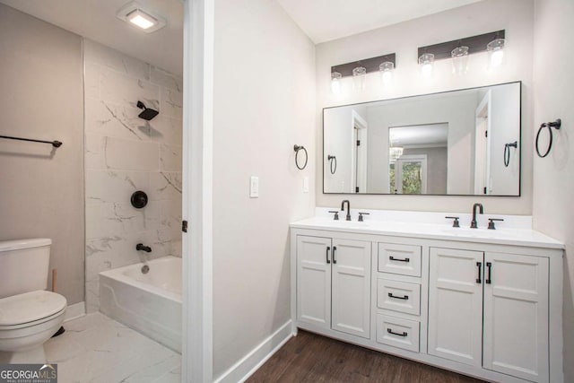 full bathroom with hardwood / wood-style floors, vanity, tiled shower / bath combo, and toilet