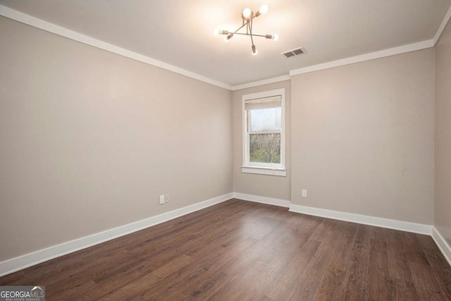 spare room featuring crown molding, dark hardwood / wood-style floors, and a notable chandelier