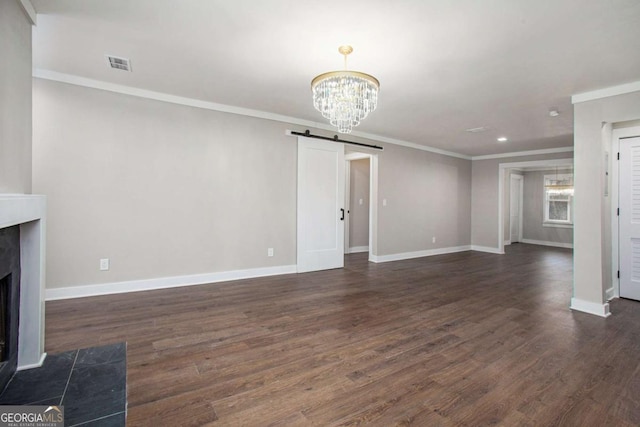 unfurnished living room featuring a chandelier, a barn door, dark hardwood / wood-style floors, and ornamental molding