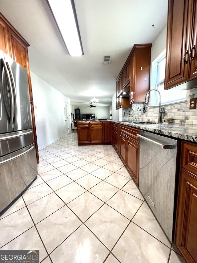 kitchen featuring ceiling fan, sink, stainless steel appliances, backsplash, and stone countertops