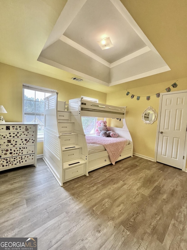 bedroom with a raised ceiling and light hardwood / wood-style flooring