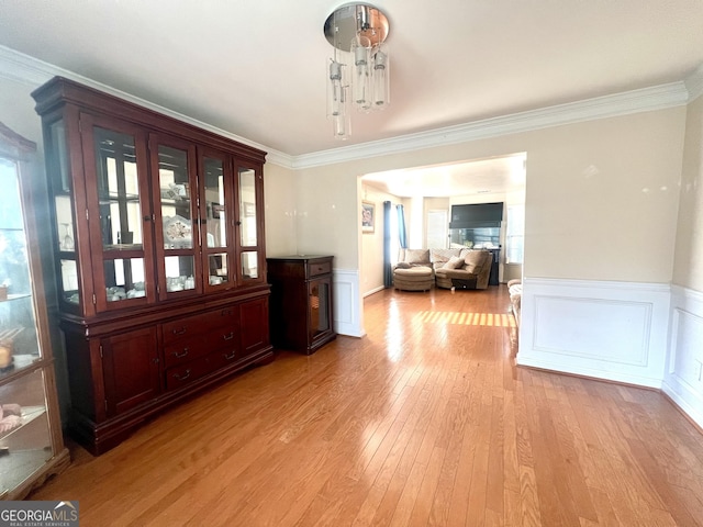 unfurnished dining area featuring light wood-type flooring and crown molding