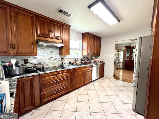 kitchen with decorative backsplash, light stone countertops, sink, dishwasher, and white fridge