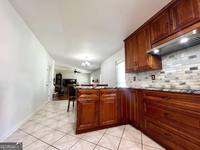 kitchen featuring ventilation hood, ceiling fan with notable chandelier, black electric stovetop, light tile patterned flooring, and kitchen peninsula