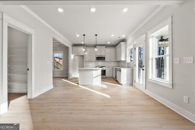 kitchen featuring a kitchen island, white cabinetry, sink, hanging light fixtures, and stainless steel appliances