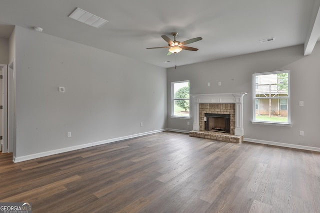 unfurnished living room featuring ceiling fan, dark hardwood / wood-style flooring, and a brick fireplace