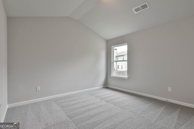 carpeted spare room with lofted ceiling