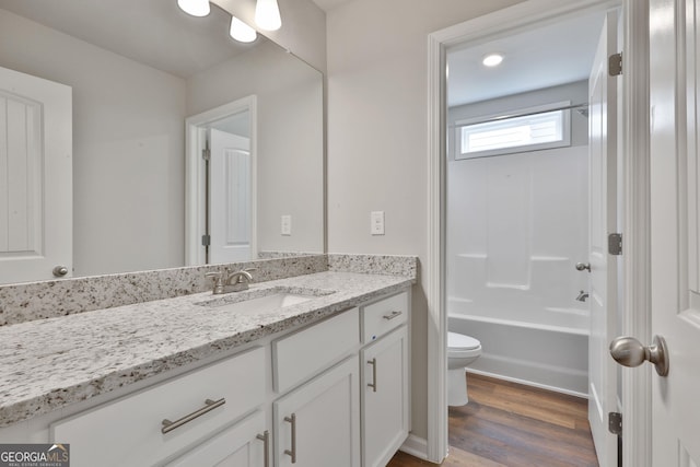 full bathroom featuring hardwood / wood-style flooring, vanity, washtub / shower combination, and toilet