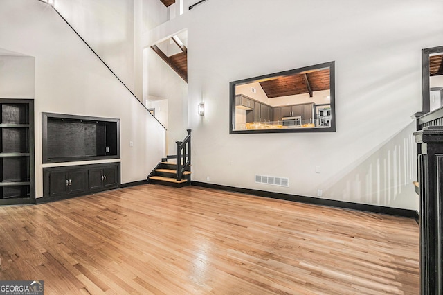 unfurnished living room featuring a fireplace, light wood-type flooring, and high vaulted ceiling