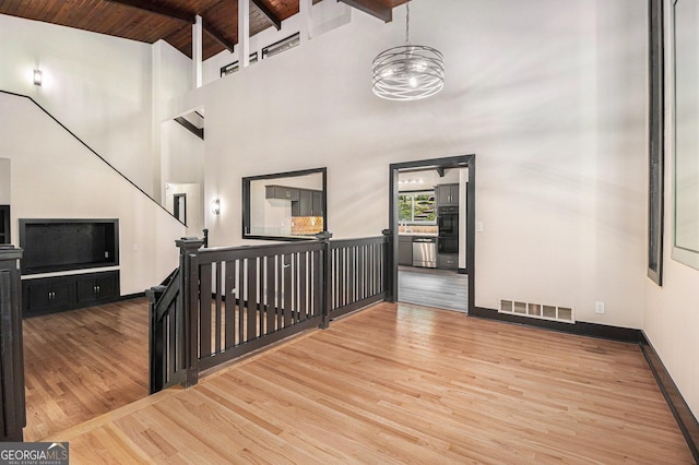 stairs featuring hardwood / wood-style floors, beam ceiling, wooden ceiling, and high vaulted ceiling