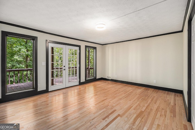 unfurnished room with light hardwood / wood-style floors, ornamental molding, a textured ceiling, and french doors