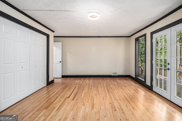 unfurnished bedroom with light hardwood / wood-style flooring, crown molding, a textured ceiling, access to outside, and a closet