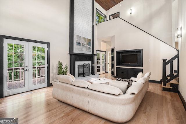 living room with a fireplace, high vaulted ceiling, french doors, and hardwood / wood-style flooring