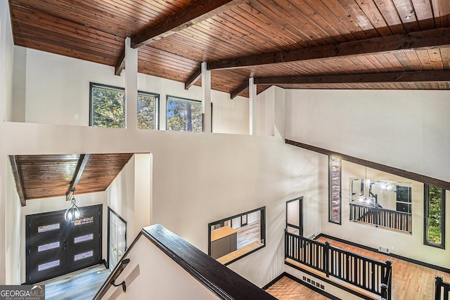 stairs with beamed ceiling, wood-type flooring, high vaulted ceiling, and wooden ceiling